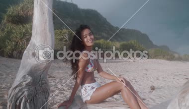 Şaşırtıcı günbatımı - ağır çekimde video sırasında düşmüş ağaç kumlu Plajı'nda oturan güzel mutlu kız