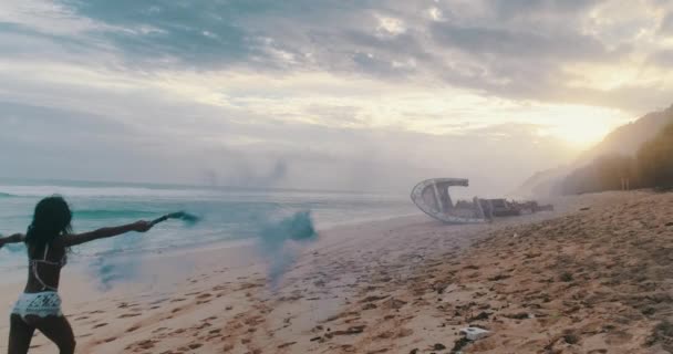 空中无人机视图美丽的女孩玩有色烟雾附近的沉船在海滩期间惊人的日落 视频慢动作 — 图库视频影像