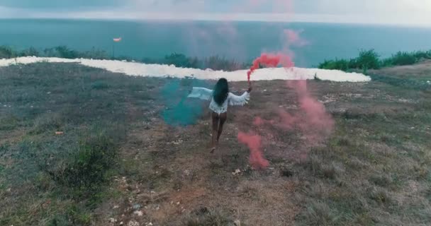 空中无人机视图美丽的女孩与有色烟雾在山上玩海洋和多云的天空背景 视频慢动作 — 图库视频影像