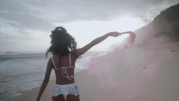 搭載した美しい幸せな女の子は色すばらしい夕日 スローモーションのビデオ中の砂浜のビーチで煙 — ストック動画