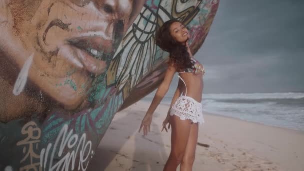 驚くべきサンセット スローモーションのビデオの間に砂浜のビーチでの難破の隣に立っている美しい少女 — ストック動画