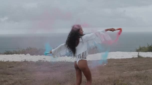 美丽的女孩与有色烟雾在山上玩海洋和多云的天空背景 视频慢动作 — 图库视频影像
