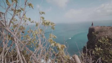 Güzel kız muhteşem okyanus ve bulutlu gökyüzü görünümü - ağır çekimde video uçurumdaki ayakta