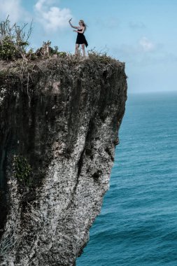 Güzel kız selfie fotoğraf muhteşem okyanus ve bulutlu gökyüzü manzaralı uçurumdaki dururken yapıyor
