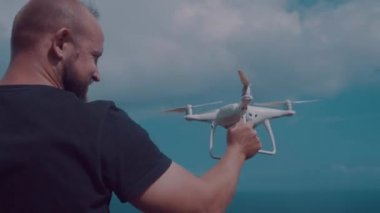 Adam alıcı dron bulutlu yaz gökyüzü arka plan karşı. Gezgin blogger Nusa Penida, Bali, Endonezya güzel Kelingking Beach kayalıklardan görüntülerini yapıyor