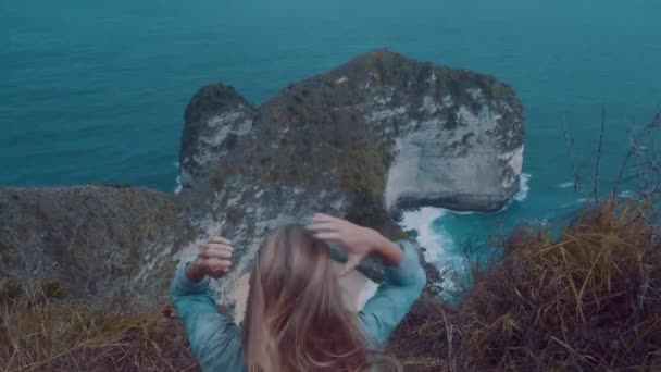 Задній Вид Дівчина Сидить Скелі Над Красиві Kelingking Пляжу Скель — стокове відео