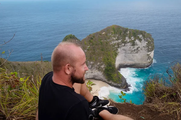 ペニダ島 インドネシア バリ島で美しい Kelingking ビーチの崖の背景の上の崖の上に男の背面図 — ストック写真