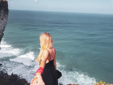 Görünümü kadın erkek arkadaşının elini dururken üzerinde güzel okyanus ve gökyüzü arka plan cliff üzerinde tutarak geri