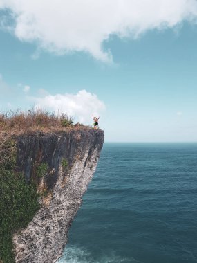 Uçurumdaki muhteşem okyanus ve bulutlu gökyüzü görünümü ile ayakta kaldırdı elleriyle mutlu çift