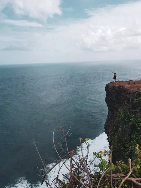 Kız muhteşem okyanus ve bulutlu gökyüzü manzaralı uçurumdaki kaldırdı elleriyle ayakta