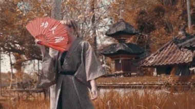 Güzel moda kız kırmızı el fan poz ile kimono geleneksel Balinese tapınak açık. Şık hippi erkek açık portresi