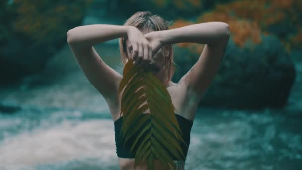 美丽的时尚女孩摆姿势 身体和脸上布满泥在热带雨林丛林附近的瀑布池塘 时尚时髦女性户外肖像 — 图库视频影像