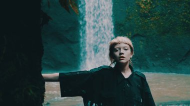 Tropik yağmur ormanı jungle şelale yanında poz kız güzel moda. Şık hippi erkek açık - dikey video portresi