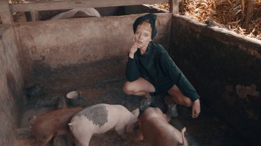 Domuz yavruları besleme ve küçük pis domuz çiftliğinde poz güzel moda kız. Şık hippi erkek portresi