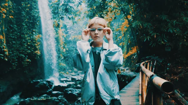 Şelalenin yanındaki tropikal yağmur ormanlarında poz veren güzel moda kızı. Açık havada şık hippi kadın portresi.