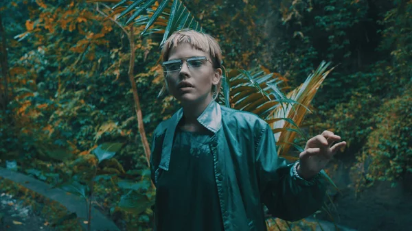 Şelalenin yanındaki tropikal yağmur ormanlarında poz veren güzel moda kızı. Açık havada şık hippi kadın portresi.