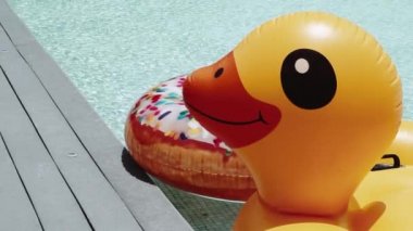 Şişme sarı ördek ve renkli halka açık yüzme havuzunda