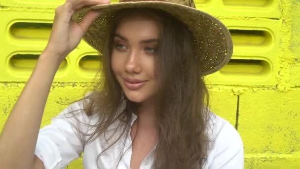 穿白色礼服的微笑女孩的时尚美丽的画像和草帽隔离在明亮的黄色墙壁 — 图库视频影像