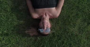 Mutlu kadın dinlendirici hava üstten görünüm güneşli yaz gün boyunca çimlerin üzerine. Uçak geliyor ise onun güneş gözlüğü alıyor - yaz relax kavram video