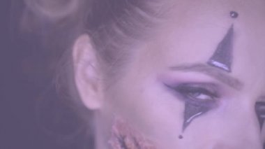 Kameraya bakarak ürpertici Halloween palyaço makyaj kadınla closeup yüzü. Yaratıcı, sanatsal, Cadılar Bayramı kavramı - ağır çekim video