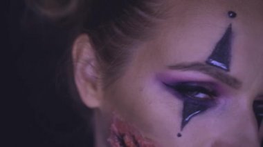 Kameraya bakarak ürpertici Halloween palyaço makyaj kadınla closeup yüzü. Yaratıcı, sanatsal, Cadılar Bayramı kavramı - ağır çekim video