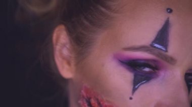 Kameraya bakarak ürpertici Halloween palyaço makyaj kadınla closeup yüzü. Yaratıcı, sanatsal, Cadılar Bayramı kavramı - ağır çekim video