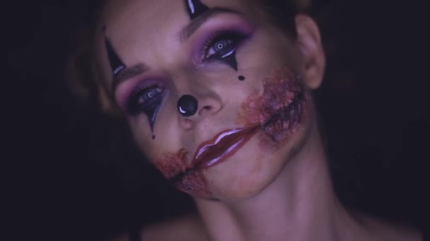 カメラに不気味なハロウィーン ピエロ化粧と女性の顔をクローズ アップ 創造的 芸術的 ハロウィーン コンセプト スローモーションのビデオ — ストック動画