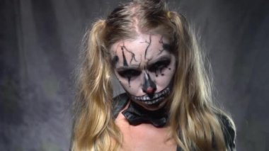 Kadının silahı kameraya dönük ve seyir ürpertici Halloween palyaço kafatası makyaj ile portre yüz. Yaratıcı, sanatsal, Cadılar Bayramı kavramı - ağır çekim video