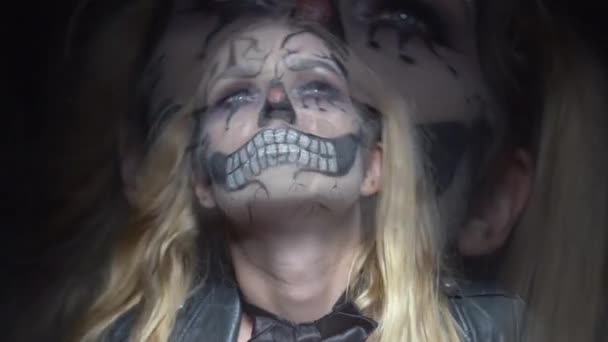 カメラに探している不気味なハロウィーン ピエロ頭蓋骨メイクと女性の顔をクローズ アップ 創造的 芸術的 ハロウィーン コンセプト スローモーションのビデオ — ストック動画