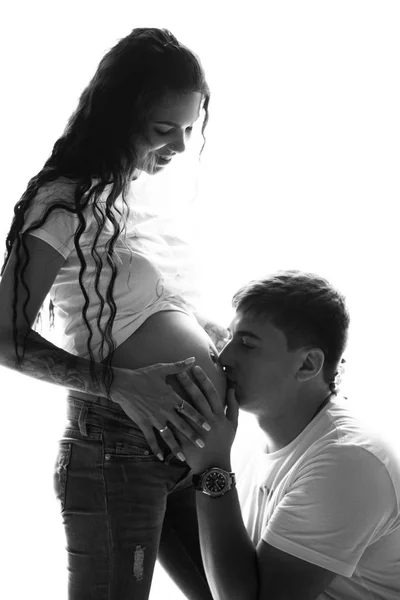 家で一緒に時間を過ごす陽気な結婚して妊娠しているカップルの肖像画 将来のお父さんが彼の妊娠中の妻 黒と白のイメージの腹にキス — ストック写真