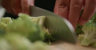 Küçük parçalar halinde taze brokoli kadar keskin bıçak ile kesme. Closeup aşçı brokoli florets ahşap kesme tahtası - ağır çekimde video üzerinde hazırlanıyor