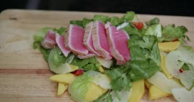 Closeup kadının koyarak taze salata somon fileto kızarmış eller. Papaya salatası - ağır çekimde video taze somon steak hazırlanıyor Şef closeup