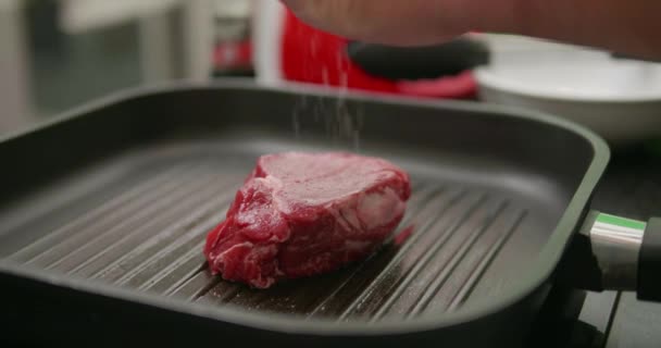 おいしい紅鮭ステーキ グリル鍋を調理します スローモーションでビデオの新鮮なヒレ肉を塩とコショウを振りかける女性シェフの手のクローズ アップ — ストック動画
