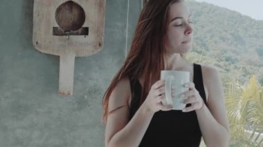 -Ağır çekimde video onun modern evinde kahve veya tee içme güzel kızıl saçlı kız portresi