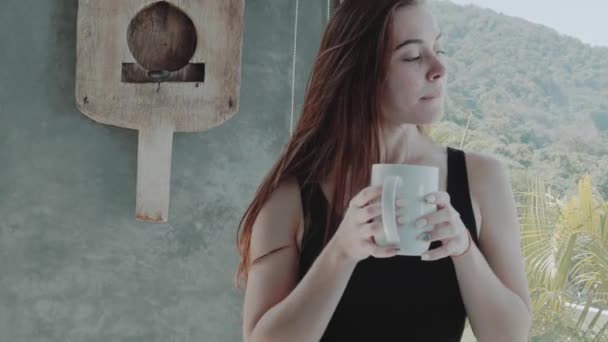 彼女の現代アパート スローモーションのビデオでコーヒーやティーを飲んで美しい赤い髪の少女の肖像画 — ストック動画