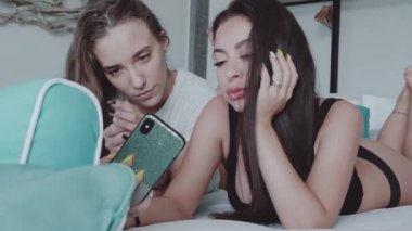 Mutlu kadın arkadaşlar modern iç ev yatakta yatarken selfie fotoğraf yapıyor. Serbest zaman, hafta sonu konseptiyle arkadaşlarım - ağır çekim video