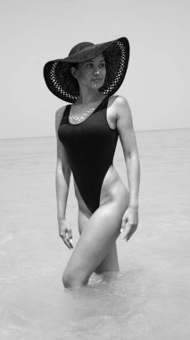 Deniz suyu duran güzel kadın. Mayo ve onun tatil - siyah ve beyaz fotoğraf keyfini hasır şapka giyen kız