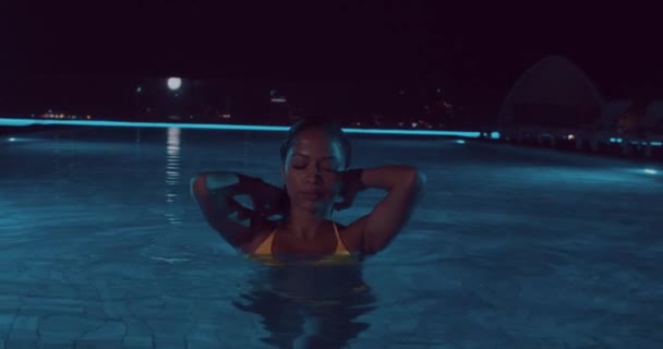 屋外スイミング プールで夜 スローモーションのビデオの間にポーズをとって黄色ビキニで美しい女性 — ストック動画