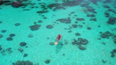 Şaşırtıcı kristal berraklığında deniz suyu üzerinde kayık köpek ile çift havadan drone görünümü