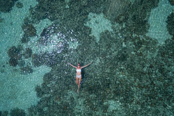 サンゴ礁と透明な海の水に浮かぶ女性の空中ドローントップビュー — ストック写真