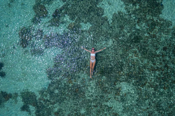 サンゴ礁と透明な海の水に浮かぶ女性の空中ドローントップビュー — ストック写真