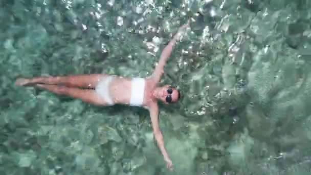 サンゴ礁と透明な海の水に浮かぶ女性の空中ドローントップビュー — ストック動画