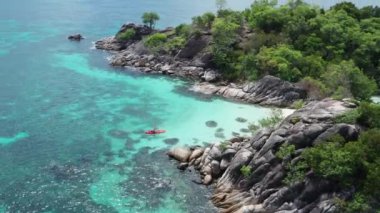 Tayland Koh Kra adası yakınlarında yaz günü kristal berraklığında lagün deniz suyunda kayak adam havadan drone görünümü. Seyahat tropikal ada tatil konsepti