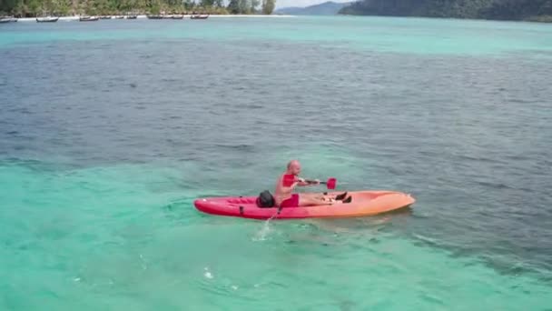 タイのクラ島近くの夏の日中に透明なラグーン海水でカヤックする人の空中ドローンビュー 旅行熱帯島の休日の概念 — ストック動画