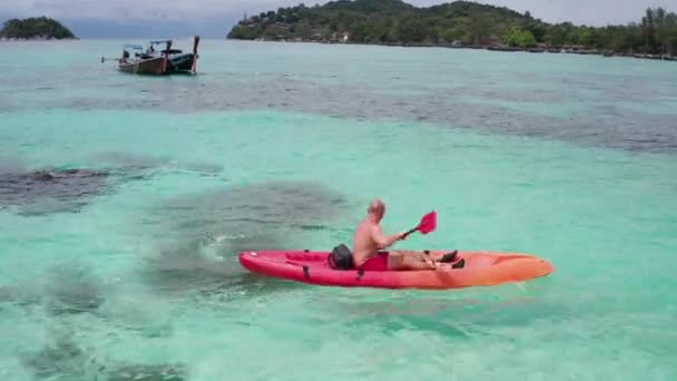 タイのクラ島近くの夏の日中に透明なラグーン海水でカヤックする人の空中ドローンビュー 旅行熱帯島の休日の概念 — ストック動画