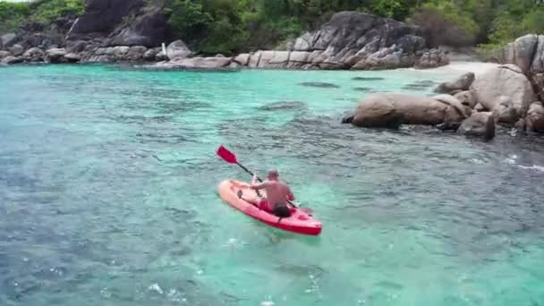 タイのクラ島近くの夏の日中に透明なラグーン海水でカヤックする人の空中ドローンビュー 旅行熱帯島の休日の概念 — ストック動画