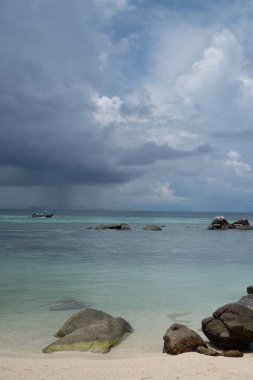 Deniz ve bulutlu gökyüzü üzerinde kayalar ile Kumlu plaj. Tayland Koh Lipe adası