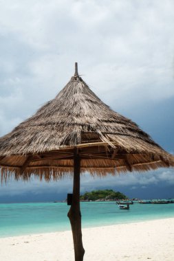 Tekneler ve küçük yeşil ada ile lagün deniz suyu üzerinde güzel kumlu plajda Şemsiye. Tayland Amazing egzotik Koh lipe ada. Tropikal tatil, tatil, seyahat konsepti