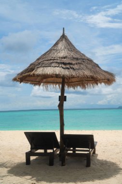 Şezlonglar, lagün deniz ve gökyüzü arka plan üzerinde şemsiye ile Amazing tropikal plaj. Tropikal tatil, tatil, seyahat konsepti