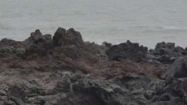 Deniz dalgaları arka plan üzerinde keskin kayalar ile Plaj